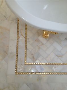 a white sink sitting next to a marble counter top with gold trimmings on it