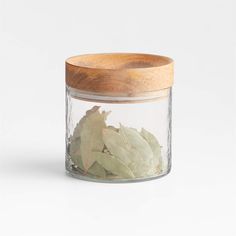 a glass jar filled with leaves and a wooden lid