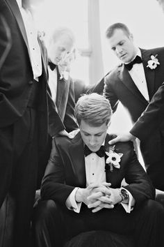 a man in a tuxedo looking at his cell phone while others look on