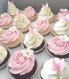 there are many cupcakes with pink and white frosting on them in the box