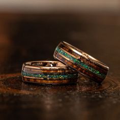 two wedding bands with green and brown wood inlays on top of each other