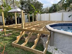 an above ground swimming pool being built in a backyard with a deck and hot tub