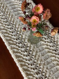 a vase filled with flowers sitting on top of a table next to a white crocheted cloth