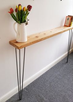 a vase with flowers sitting on top of a long wooden table next to a book shelf