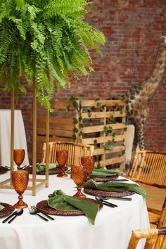 a giraffe is in the background behind a table with place settings on it