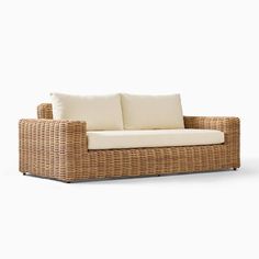 a wicker couch with two pillows on it's back and the seat upholstered