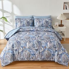 a blue and white comforter set on a wooden floor