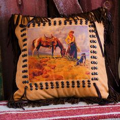 a decorative pillow with an image of a woman and her horse on it, sitting next to a wooden fence