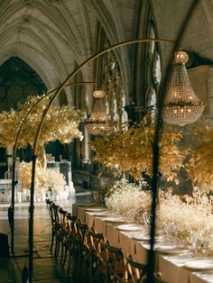 the tables are set up for a formal function in an old building with chandeliers hanging from the ceiling