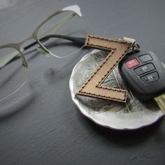 a pair of glasses sitting on top of a plate next to a keychain