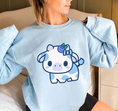 PLEASE NOTE:  This is a UNISEX sweater.  If you want an oversized look then consider ordering up a size. This cute blueberry cow sweater will look adorable on you!  Makes for a great kawaii gift for your loved ones as well. The collar is ribbed knit, so it retains its shape even after washing. There are no itchy side seams on these sweaters.  .: 50% cotton, 50% polyester .: Medium-heavy fabric (8.0 oz/yd² (271.25 g/m .: Loose fit .: Sewn-in label .: Runs true to size Oversized Kawaii Sweatshirt With Cartoon Print, Oversized Kawaii Cartoon Print Sweatshirt, Blue Harajuku Cotton Sweatshirt, Blue Cotton Harajuku Sweatshirt, Blue Long Sleeve Kawaii Sweatshirt, Cute Blue Sweatshirt With Graphic Print, Cute Oversized Blue Tops, Blueberry Outfit, Cow Merch