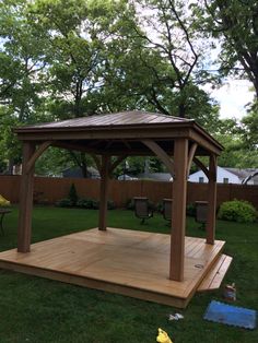 a wooden gazebo sitting on top of a lush green field