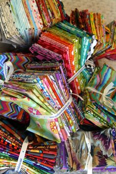 a pile of multicolored fabric sitting on top of a table next to scissors