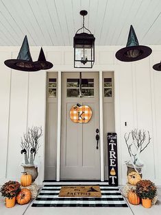 a front porch decorated for halloween with pumpkins and other decorations on the door mat