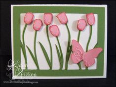 a card with some pink flowers and a butterfly on the front, and green grass in the back