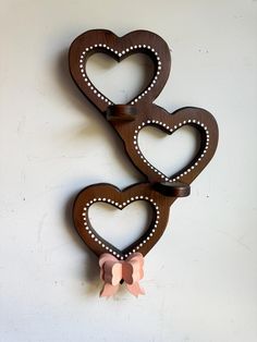 two wooden heart shaped wall hangings with bows on each one's sides, set against a white wall