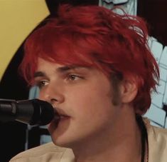 a man with red hair is singing into a microphone