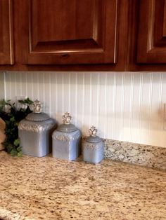 three canisters sitting on top of a granite countertop in a home kitchen