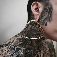 a man with tattoos and piercings on his neck is wearing a heart shaped earring