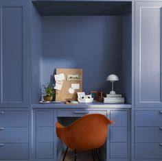 an orange chair sitting in front of a desk with a lamp on top of it