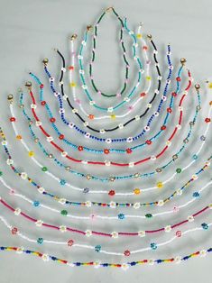 multicolored beaded necklaces are arranged on a white surface with beads in the shape of a triangle