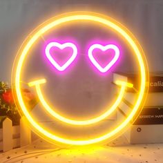 a neon sign with two hearts in the shape of a smiley face on top of a table