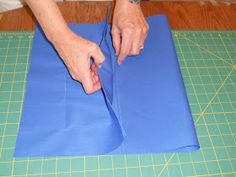 a person cutting up blue paper on top of a table