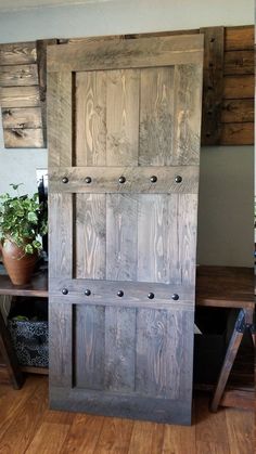 an old wooden door sitting on top of a hard wood floor next to a potted plant