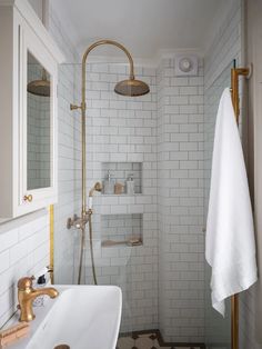 a bathroom with white tile and gold fixtures