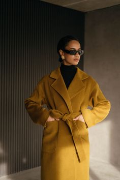 Our mustard gold wrap coat with the loose fit. The H silhouette adds versatility and timeless appeal to your ensemble. With two practical patch pockets, this coat combines convenience and style, allowing you to keep your essentials close at hand. The included belt emphasizes your waist while creating a beautiful and feminine silhouette that accentuates your figure.  Wrap style Loose fit H-silhouette Lowered shoulders line 2 patch pockets Belt Coat fabric: wool 100% Lining fabric: 100% viscose If Luxury Fall Outerwear For Fashion Statement, Luxury Camel Outerwear For Work, Timeless Luxury Solid Color Outerwear, Luxury Orange Formal Outerwear, Luxury Modern Wool Coat For Fall, Luxury Elegant Camel Wool Coat, Luxury Mustard Winter Outerwear, Luxury Outerwear For Fall Fashion Statement, Fitted Luxury Yellow Outerwear