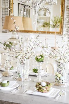 an easter table with eggs and flowers in vases