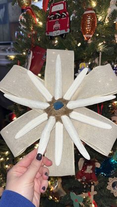 a person holding up a piece of fabric to make a flower ornament on a christmas tree