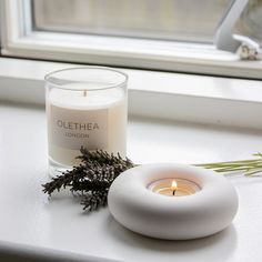 a candle sitting on top of a window sill next to a plant