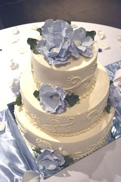 a wedding cake with blue flowers on top