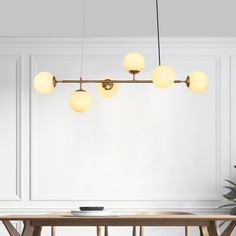 a dining room with a wooden table and four lights hanging from it's ceiling