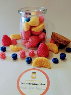 a jar filled with raspberries and blueberries on top of a white table