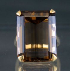 Presented is an eye-catching 14 karat yellow gold and smoky quartz cocktail    ring. This ring dates to around the 1950s and is likely of American make. The    ring is set with a rectangular or emerald-cut smoky quartz, measuring about 22    by 17.5 by 13 millimeters, or about 33.5 carats. Quite a large and impressive    stone, beautifully cut and faceted.      The interior of the band is stamped 14 for 14 karat gold, nitric acid tested    and guaranteed.     The ring is in great condition. The Rhodolite Garnet Ring, Smoky Quartz Ring, Smoky Topaz, Silver Bowl, Rhodolite Garnet, Star Ring, Quartz Ring, Garnet Rings, Smokey Quartz