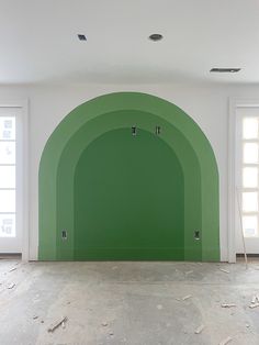 an empty room with green arches painted on the wall