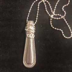 a silver necklace with an ornate design on the end and a chain attached to it