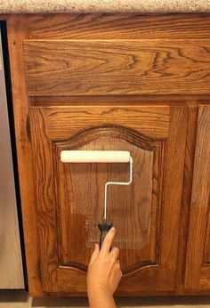 a person using a paint roller to paint cabinet doors with text overlay that reads the hottest new way to paint cabinets