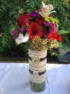 a vase filled with red and purple flowers on top of a white cloth covered table