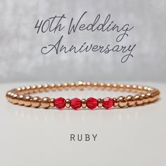 "An elegant and dainty stacking bracelet in Rose Gold Fill accented with Rubies which are the traditional gift to celebrate a 40th wedding anniversary. This Ruby and Gold stretchy layering bracelet is a lovely and subtle way to celebrate a very special 40th Ruby Wedding Anniversary with three Ruby Swarovski Crystals, one to represent and celebrate each amazing decade spent together. Also included will be a jewellery card showing the special anniversary and the meaning behind the four crystals as shown on the product images. All the beads on this bracelet are rose gold filled and the round beads are 4mm, the crystals are genuine Swarovski with amazing sparkle and are also 4mm. The beads are strung on stretchy high quality jeweller's elastic. The bracelet is sized to fit most wrist sizes aro Elegant Rose Gold Beaded Bracelets For Anniversary, Classic Bracelets For Anniversary On Valentine's Day, Rose Gold Jubilee Bracelet For Anniversary, Classic Birthstone Bracelets For Anniversary, Anniversary Rose Gold Stackable Bracelets, Elegant Wedding Beaded Bracelets With Birthstone, Anniversary Stackable Rose Gold Bracelets, Elegant Beaded Bracelets With Birthstone For Wedding, Elegant Beaded Bracelets For Valentine's Day Anniversary