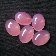 four pink stones sitting on top of a black cloth covered floor next to each other