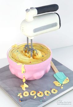 a cake made to look like a mixer with yellow icing and sprinkles