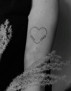 a black and white photo of a woman's arm with a heart tattoo