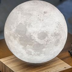 the moon lamp is on top of a wooden stand