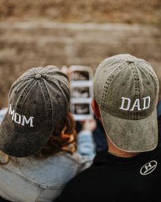 a man and woman wearing baseball caps with the word dad written on them