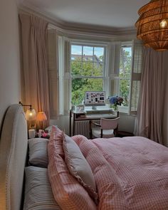 a bedroom with a bed, desk and two lamps on either side of the window