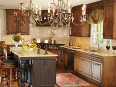 a chandelier hanging from the ceiling in a kitchen with wooden cabinets and an island