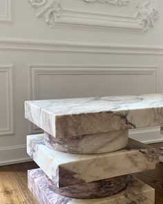 three stacked marble blocks in front of a white wall